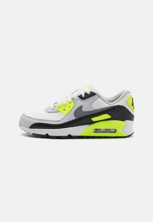 Biały, szary, czarny i neonowożółty but sportowy Nike Air Max z widoczną podeszwą powietrzną i logo Nike po boku.