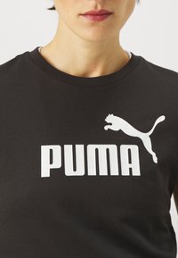 Black cotton t-shirt featuring a large white "PUMA" logo and a leaping puma silhouette on the chest. Classic crew neck design.