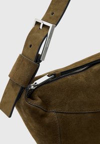 Sezione di borsa in suede marrone con una finitura testurizzata, caratterizzata da una fibbia in metallo color argento e una chiusura con zip lungo il lato.