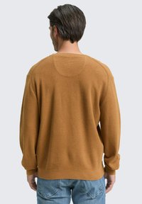 Jersey marrón de punto con un acabado texturizado, cuello redondo y costuras de hombro caídas. Mangas y dobladillo acanalados, mostrado desde la parte posterior.