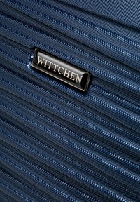 Marineblauwe harde koffer met een gestructureerde afwerking, voorzien van horizontale ribbels en een zwart merkteken met de naam "Wittchen."