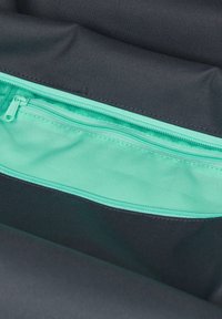 Schwarzer Stoff-Rucksack mit einem Inneren, das eine türkisfarbene Reißverschlusstasche mit glatter Textur und Nähdetails aufweist.