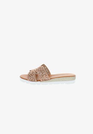 Sandalo beige slip-on con cinturino traforato impreziosito da borchie rotonde, sottopiede imbottito, intersuola intrecciata e suola esterna in gomma bianca.