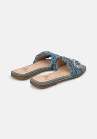 Sandali a scivolo in denim con bordi sfrangiati, arricchiti da una fascia di gioielli. Suola piatta con base color tan e soletta liscia.