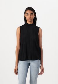 Haut sans manches noir avec un col montant et des plis verticaux, en tissu léger ; associé à un jean bleu délavé avec des détails usés.