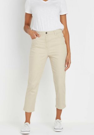 Beige cotton blend cropped pants with a straight cut, front pockets, and a button closure, paired with a white v-neck t-shirt and sneakers.