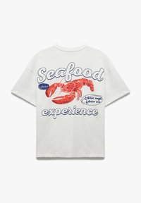 Hvid bomulds t-shirt med et rødt hummer grafik og blå tekst med påskriften "Seafood experience" og "Lobster magic". Korte ærmer, afslappet pasform.