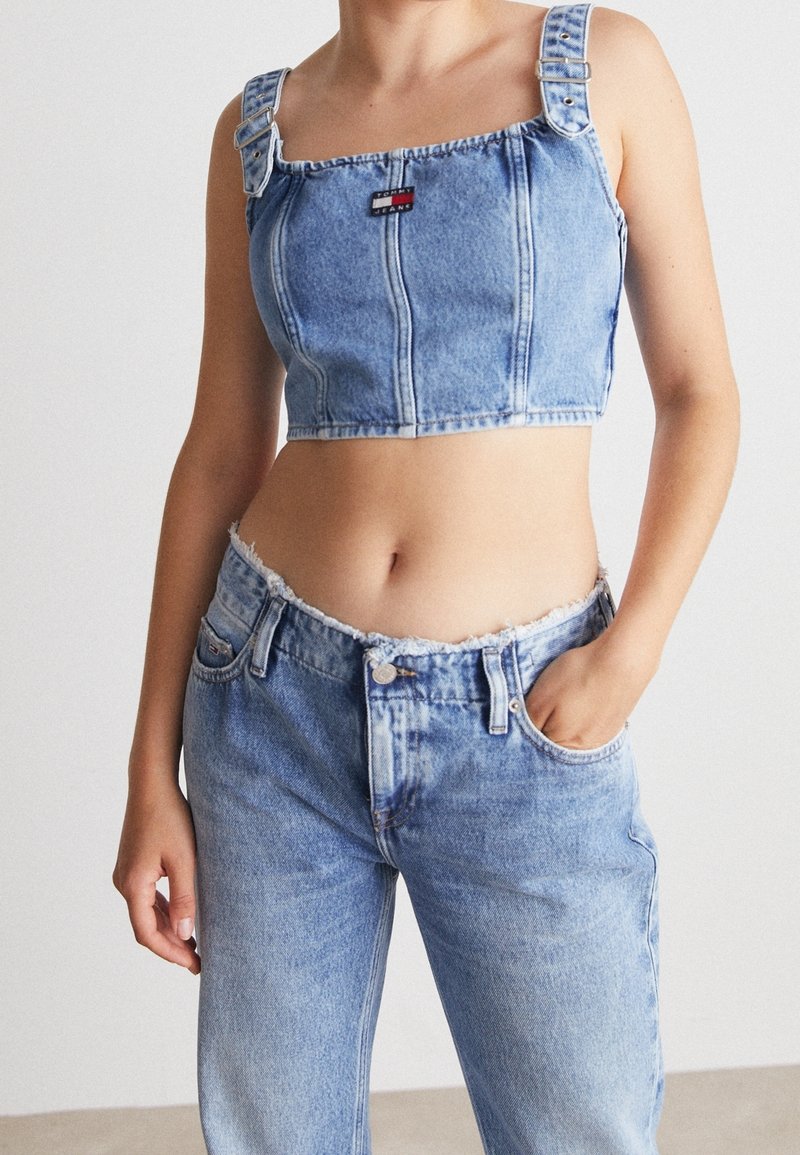 Denimowy crop top z regulowanymi ramiączkami, kwadratowym dekoltem i centralną łatą z logo. Jeansy o wysokim stanie z postrzępionym dołem w jasnoniebieskim odcieniu, luźny krój.