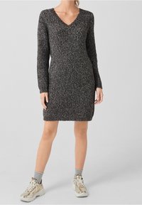 Grey knitted dress with a V-neck, long sleeves, and a ribbed texture. Paired with silver sneakers and grey ankle socks.