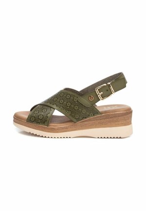 Sandalo in pelle verde perforata con cinturini incrociati, fibbia regolabile e una suola a zeppa robusta con un motivo in legno testurizzato.