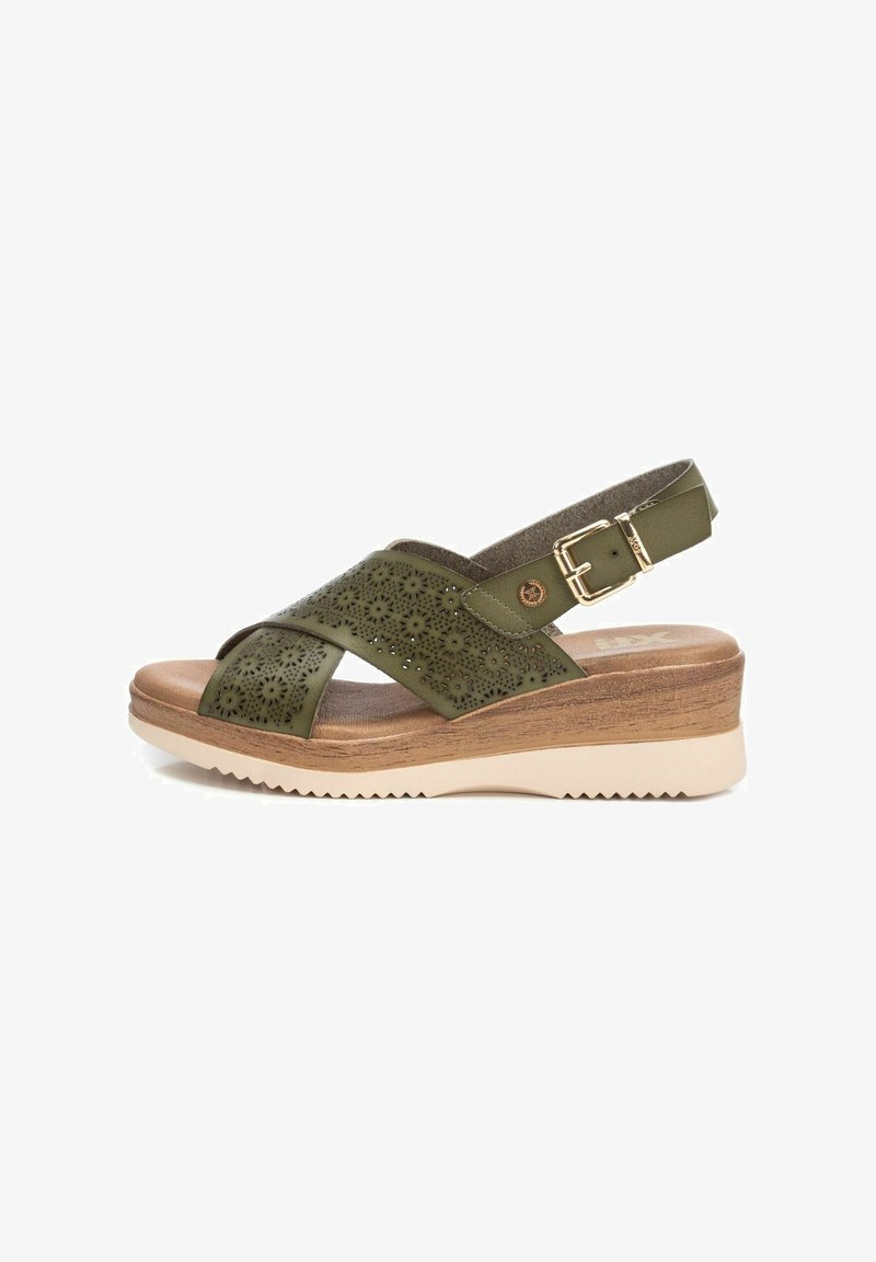 Sandalo in pelle verde perforata con cinturini incrociati, fibbia regolabile e una suola a zeppa robusta con un motivo in legno testurizzato.