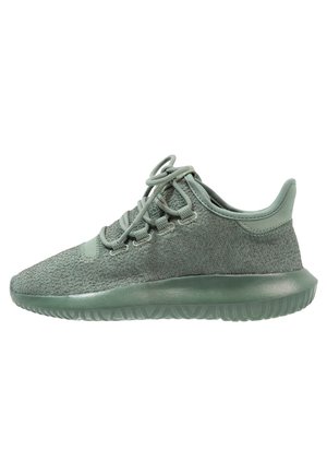 Lichtgroene sportieve sneaker met een gebreide bovenkant, vetersluiting en een dikke rubberen zool, zijaanzicht op een witte achtergrond.