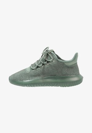Lichtgroene sportieve sneaker met een gebreide bovenkant, vetersluiting en een dikke rubberen zool, zijaanzicht op een witte achtergrond.