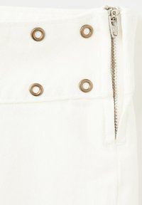 Tissu de vêtement blanc avec quatre œillets en bronze disposés en deux rangées et une fermeture éclair YKK argentée partiellement ouverte sur le côté droit.