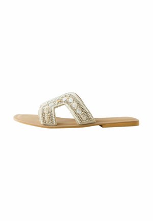 Ploché svetlohnedé šľapky s širokým krémovým remienkom zdobeným bielymi korálkami a perlami v geometrickom vzore.