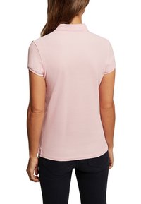 Polo rose avec un col classique, des manches courtes et un tissu texturé. Conçu avec une coupe ajustée et des fentes latérales pour plus de confort.