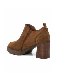 Stivaletti in suede marrone con punta arrotondata, pannelli elastici laterali e tacco in legno spesso. Sole testurizzato per una presa migliore.