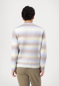 Pull en tricot présentant un dégradé de rayures pastel douces en beige, bleu et jaune, avec des poignets et une ourlet côtelés. Vue de dos affichée.