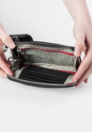 Black zippered wallet held open, featuring a geometric patterned interior, multiple card slots, and red accent stitching along the zipper.
