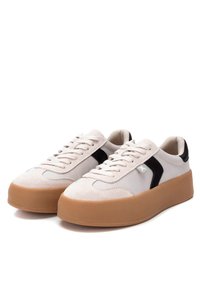 Baskets blanches et noires avec une semelle épaisse en gomme, des matériaux en daim et cuir lisse, des lacets plats, et un détail de logo sur le côté.