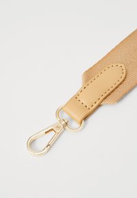 Μπεζ υφασμάτινος ιμάντας με υφή. Διαθέτει δερμάτινο μπαλάκι και χρυσό μεταλλικό κλιπ για προσαρμογή.