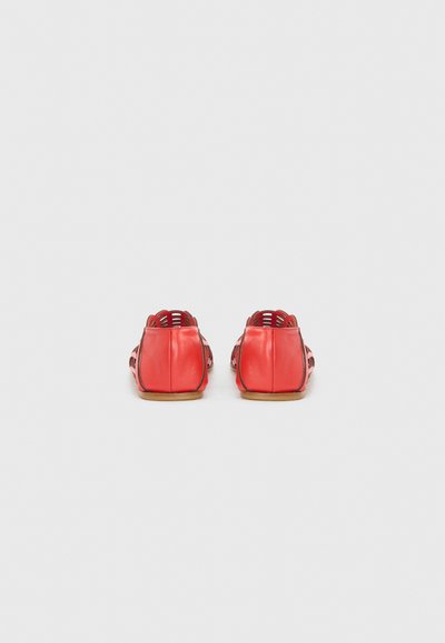 Pantofi din piele roșie cu design-uri tăiate și o textură netedă. Partea din spate are un panou solid și o talpă plată.