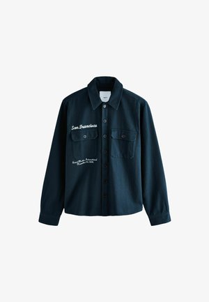 Tume roheline nööbid üles särk kahe esise tasku, bordüüritud detailide ja klassikalise kraega. Valmistatud tekstureeritud kangast.