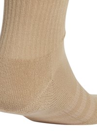 Chaussette en coton beige avec texture côtelée et coutures de orteils lisses, présentant un design ajusté au niveau de la cheville qui s'étend au-delà de la cheville.