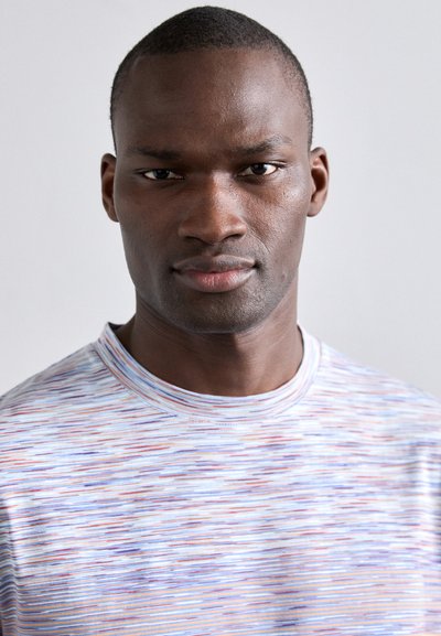 Chemise multicolore à manches courtes avec un design texturé agrémenté de rayures horizontales bleues, rouges et blanches. Encolure ronde.