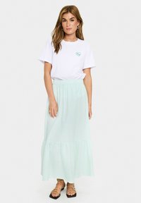 T-shirt alb cu grafică în formă de inimă verde, asortat cu o fustă lungă, de culoare verde deschis, cu dungi și tiv volănat, având talie elastică.