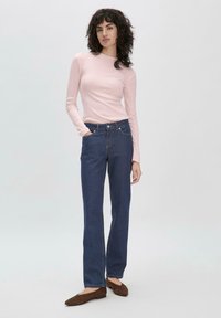 Helles rosa Langarmoberteil kombiniert mit dunkelblauen, geraden Jeans. Dunkelbraune Ballerinas runden den Look ab. Saubere Linien und figurbetonte Passform.