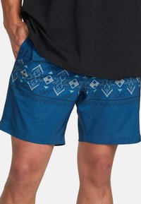Shorts de bain bleu avec un motif géométrique en bleu clair et blanc. Fabriqués en tissu léger, avec des poches latérales et une taille élastique.