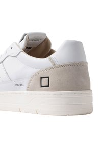 Hvide lædersneakers med grå ruskindshæl, med sort firkantet detalje, polstret krave og hævet hvid sål. Designet har rund tå.