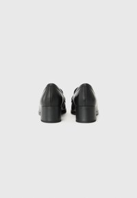 Black leather shoes with a rounded toe, low block heel, smooth texture, and minimalistic design, featuring a slightly raised back.