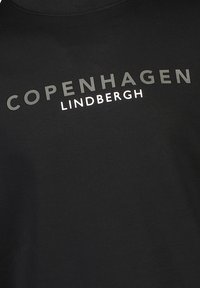 Camiseta de algodón negra con cuello redondo y texto impreso "COPENHAGUE LINDHBERGH" en colores contrastantes. Textura suave.