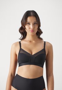 Schwarzer BH mit Netzdetails und V-förmigem Design, verstellbaren Trägern und einem weichen Bündchen am unteren Ende. Glattes, dehnbares Material.