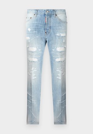 Jean slim bleu clair avec des patchs usés et des détails délavés, fermeture avant par bouton et fermeture éclair, et design à cinq poches.