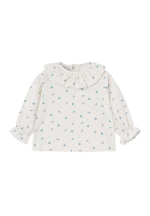 Blouse blanche à manches longues avec un col volé, ornée d'un motif de petits éléments bleus sur un fond clair.