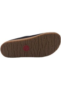 Black shoe sole with textured rubber material, featuring a circular red logo and a beige midsole, designed for stability and traction.