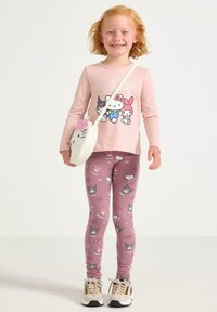 Rosa långärmad skjorta med Hello Kitty-grafik, kombinerad med rosa leggings med Hello Kitty-mönster. Vit axelremsväska formad som en katt.
