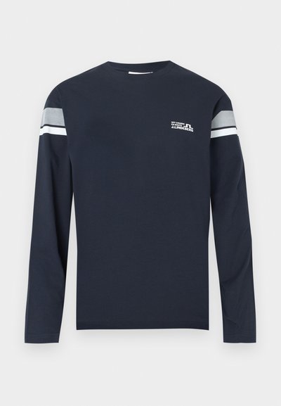 Granatowa koszulka z długim rękawem wykonana z bawełnianej tkaniny, z okrągłym dekoltem, białym i szarym paskiem na rękawach oraz małym logo na piersi.