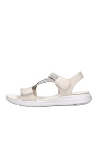 Sandal in beige con una fascia testurizzata, chiusura regolabile in velcro e una suola bianca flessibile. Presenta un profilo basso e un design aperto.