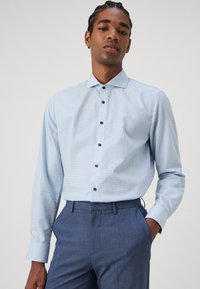 Lichtblauw geruite overhemd met donkere knopen, lange mouwen en een klassieke kraag, gecombineerd met donkerblauwe broek.