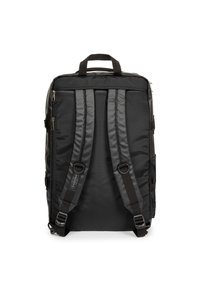 Musta reppu, joka on valmistettu kankaasta ja siinä on kaksi säädettävää pehmustettua olkahihnaa, ylimmäinen kahva ja sivun verkkotasku. Takana on vetoketjut.