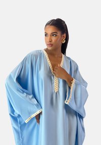 Lyseblå satin kaftan med dyb V-hals, indviklet cremekant langs halsudskæringen og ærmerne, med brede, flydende ærmer.