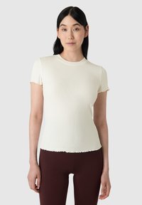 Krátký rukáv, žebrovaný kr�émový top s kulatým výstřihem a vroubkovaným lemem. Pairs with bordó legínami pro kontrast.