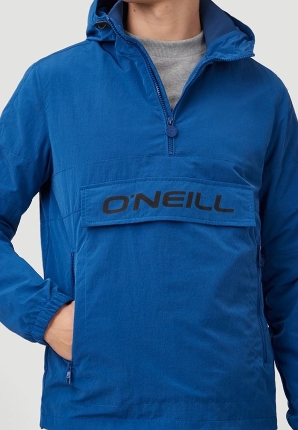 Personne portant un pull O'Neill bleu avec une fermeture éclair frontale et une grande poche à rabat avec logo.