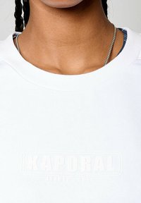 Felpa bianca a girocollo con logo in rilievo bianco "KAPORAL LEADER 2023". Tessuto testurizzato, cuciture a vista e dettaglio del collo a strati.