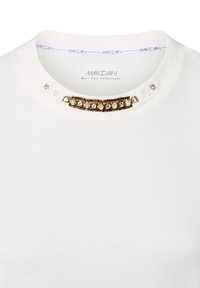 Weißes T-Shirt mit rundem Ausschnitt, verziert mit einer goldenen und kristallenen Perlenakzent am Kragen und kleinen klaren Steinen an der Schulter.