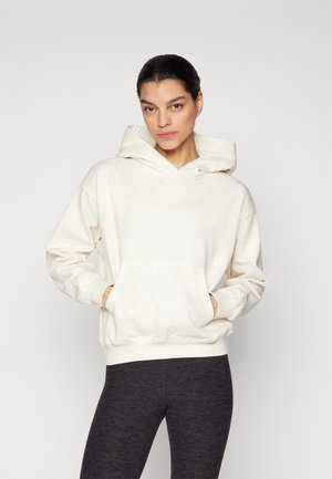 Lys beige hettegenser med kengurulomme, snøring i hetten, ribbestrikkede mansjetter og kant. Kombinert med mørkegrå tights. Mykt, teksturert stoff.